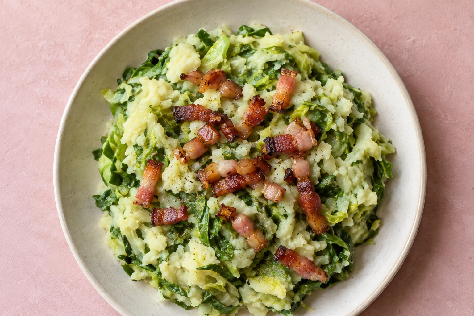 Komijnkleurig bord met stamppot andijvie en krokante spekjes, zachte aardappelpuree en groene andijviestroken